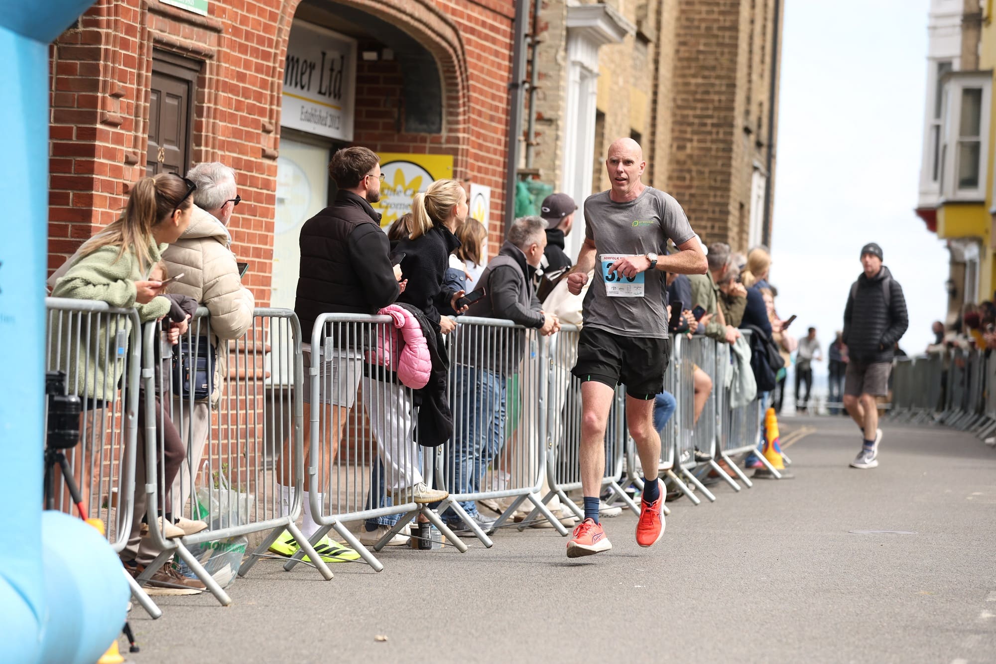 Man wearing a grey t-shirt running a marathon on a street